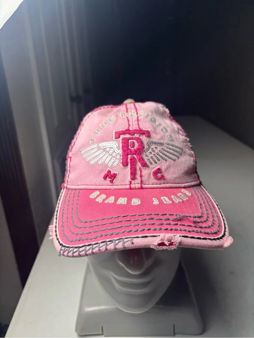 pink, distressed True Religion brand jeans cap with embroidered wings and a logo